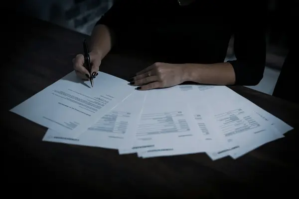 Iemand controleert een stapel facturen aan tafel